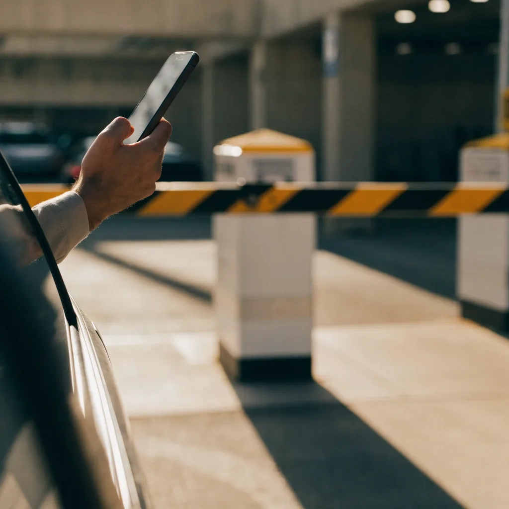 Hand with phone at car park entry barrier
